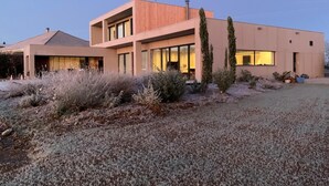 Een modern huis met twee verdiepingen, een plat dak en grote ramen.
