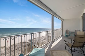 Ein Balkon mit Blick auf Strand und Meer, ausgestattet mit Stühlen und einem Tisch.