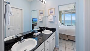 Un baño con dos lavamanos, un espejo y una cama con vistas.