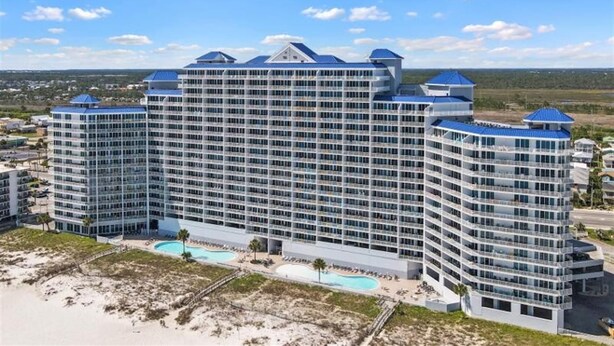 Un hotel grande de varios pisos con piscina y acceso directo a la playa.
