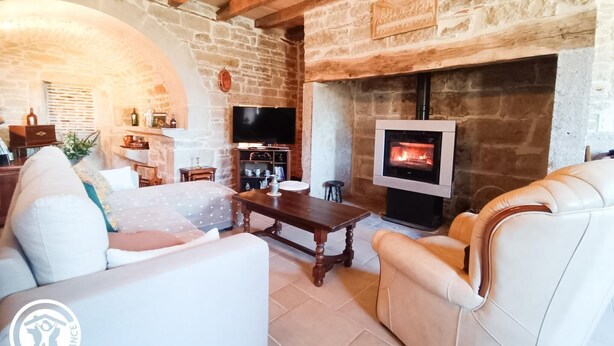 Ein gemütliches Wohnzimmer mit Steinwänden, einem Kamin, einem Fernseher und bequemen Sitzgelegenheiten.