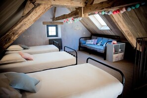 Un dormitorio acogedor en el ático con dos camas individuales, un sofá y un ventanal pequeño.