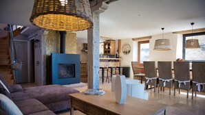 A spacious living area with a fireplace, modern furniture, and a dining area with wicker chairs. - Gîtes de France® - La Maison de Campagne (ALVIGNAC)