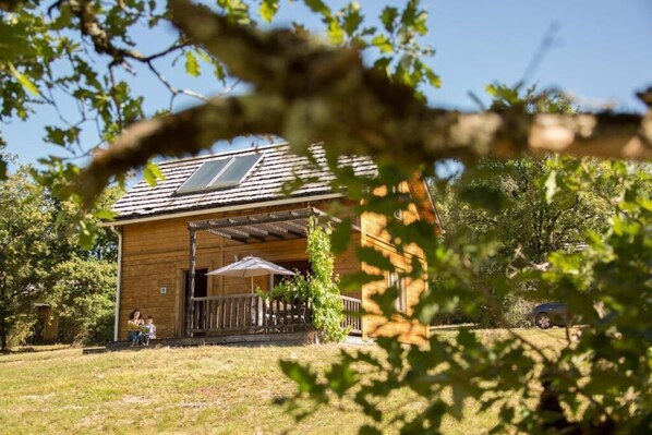 Escape to a serene cabin surrounded by lush greenery and a tranquil lawn.