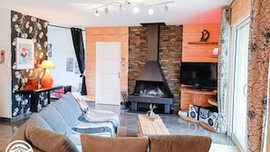 En moderne stue med sofa, sofabord, pejs, fjernsyn og en væg med mønster.