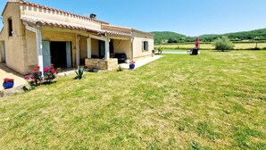 Ein Haus mit überdachter Veranda, Swimmingpool und Rasenfläche.