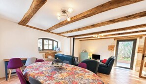 Een eethoek met een ronde tafel, stoelen en een houten plafond.