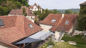 A residential area with red-tiled roofs, a stone building, and a grassy courtyard.