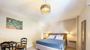 Een slaapkamer met een bed, twee wandlampen, een hanglamp en een schilderij aan de muur.