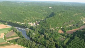 An aerial view of a rural landscape with a river, fields, and scattered buildings.