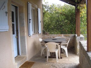 Une terrasse avec une table et des chaises, une porte et un mur en pierre.