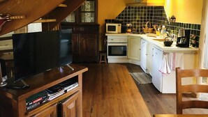 A cozy kitchen with wooden cabinets, a microwave, and a small island with a sink.