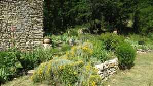A garden with a stone wall, various plants, and a statue. - 46g12089 - Maxou - Gîte (MAXOU)