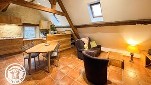 Ein gemütliches Loft-Zimmer mit Essbereich, einer Couch und einem kleinen Tisch mit Lampe.