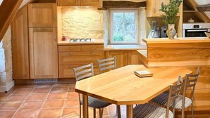Eine rustikale Küche mit Holzschränken, einer Steinwand und einem Essbereich mit Holztisch und -stühlen.