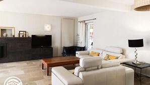 A modern living room with a sofa, a coffee table, a TV, and a lamp. - Gîtes de France® - Villa le Simonet (BETAILLE)