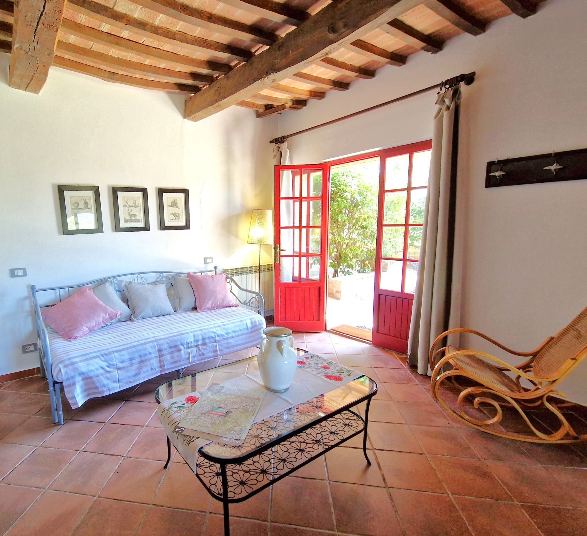 A bedroom with a bed, a table with a map, a chair, and a red door leading outside.