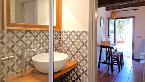 A bathroom with a large mirror, a vessel sink, and patterned tile walls. - Borgo Melograno - SOL Diesis Apartment (Toscana)