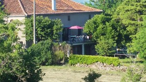 Ein Haus mit Ziegeldach, einem Balkon mit Sitzgelegenheit und einer Steinmauer im Vordergrund.