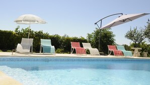 En swimmingpool med liggestole og parasoller.