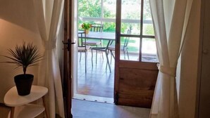 A room with a wooden door leading to an outdoor patio with a table and chairs. - Gîtes de France® - Chez Mamie (LACAVE)