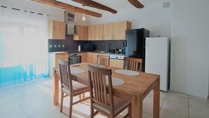 A modern kitchen with wooden cabinets, a black refrigerator, and a dining area with a wooden table and chairs.