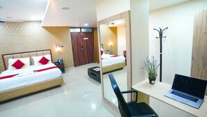 A hotel room with two beds, a desk with a laptop, a mirror, and a potted plant. - Sunrise A Boutique Hotel (Hyderabad)