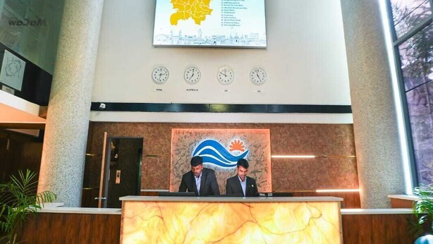 A reception area with a marble counter, two men seated behind it, and a map of Hyderabad on the wall. - Sunrise A Boutique Hotel (Hyderabad)