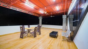 A rooftop terrace with wooden flooring, a table with chairs, and a concrete pillar. - Sunrise A Boutique Hotel (Hyderabad)