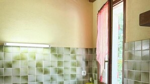 A bathroom with tiled walls, a window with a curtain, and a visible light switch.