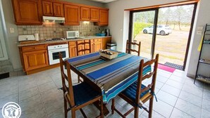 A kitchen with wooden cabinets, a dining table with a striped tablecloth, and a view of a parked car outside.