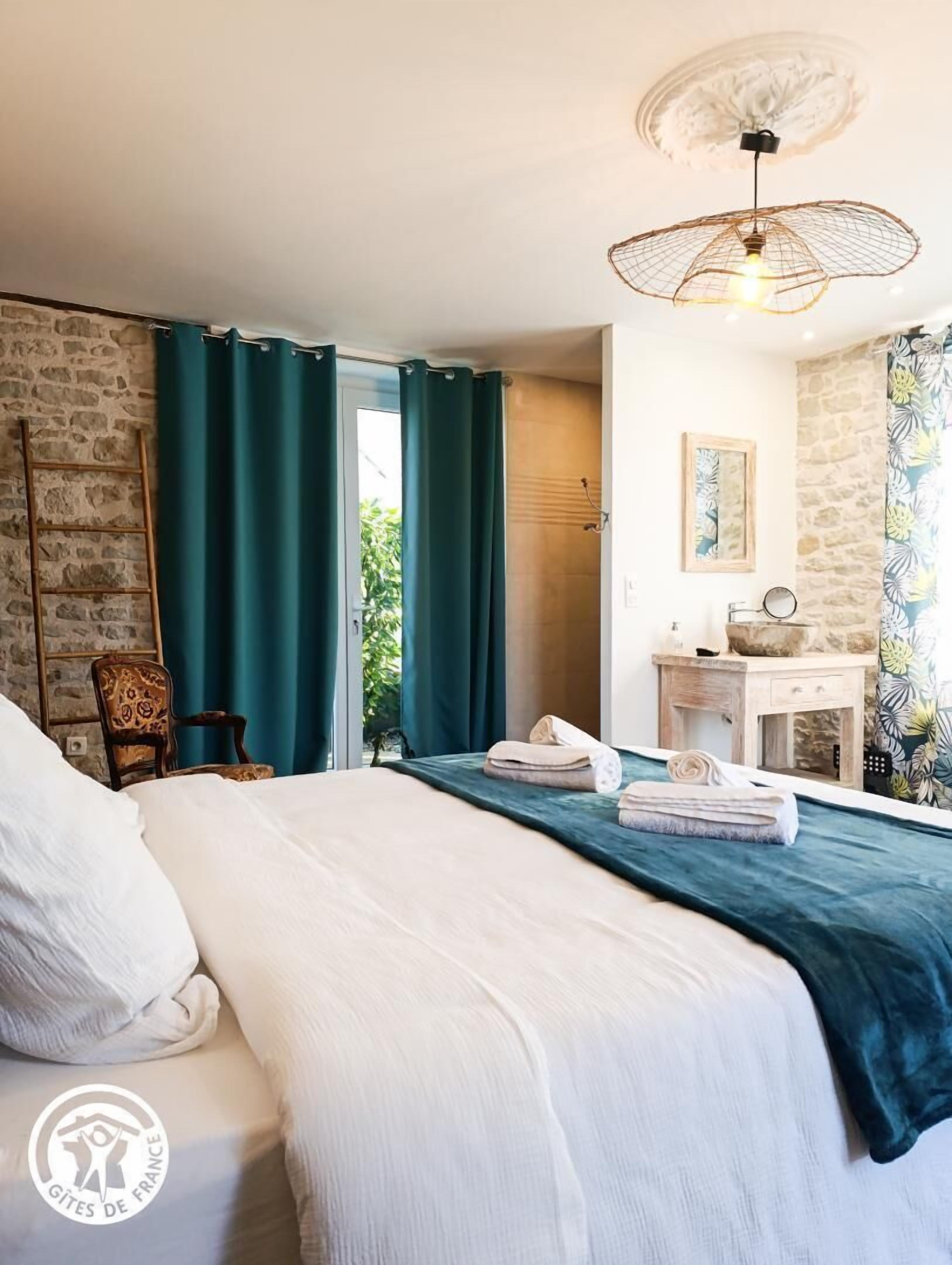 Une chambre à coucher avec un lit, un bureau, une chaise et une fenêtre avec des rideaux.