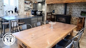 Una cucina con parete in pietra, tavolo di legno e camino.