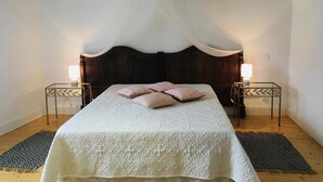 Ein Schlafzimmer mit einem großen Bett, zwei Nachttischen mit Lampen, einem Baldachin und Holzboden.
