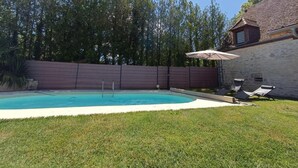 A backyard with a swimming pool, a covered patio area, and a stone wall. - Gîtes de France® - My Loft (ST CIRQ SOUILLAGUET)