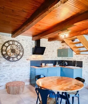 Une cuisine rustique avec des armoires bleues, un plafond en bois et un mur en pierre.