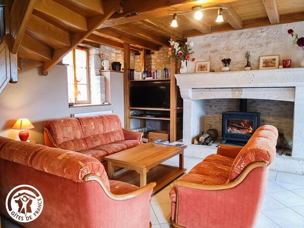 A cozy living room with a fireplace, wooden furniture, and a bookshelf.