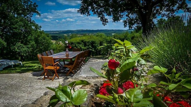 Un espace de restauration en plein air, avec une table et des chaises, entouré de verdure et offrant une vue sur la campagne.