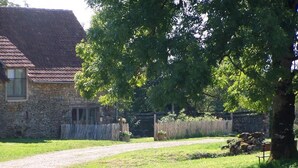 A rural stone building with a gravel driveway leading to a wooden fence. - Gîtes de France® - The Demolished Barn (ASSIER)