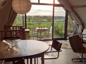 Une pièce chaleureuse avec une grande table et des chaises, un balcon offrant une vue sur la verdure et un décor intérieur de style rustique.