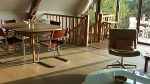 A cozy dining area with a round table, red and black chairs, and a glass table with a bowl. - Gîtes de France® - The Demolished Barn (ASSIER)