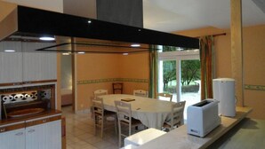 A dining area with a table and chairs, a kitchen with a stove and a toaster, and a window with curtains.