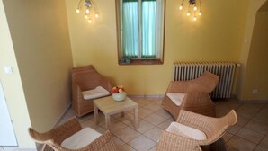 Una habitación con muebles de mimbre, una mesita con un florero y una ventana con cortinas.