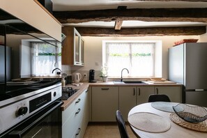 A kitchen with a stove, sink, cabinets, and a dining table with placemats.