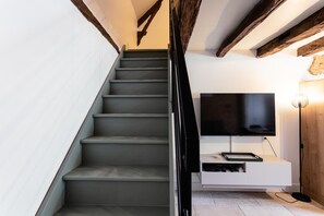 A staircase with dark steps, a black handrail, and a white wall.