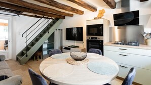 A modern kitchen with a dining area, wooden beams, a flat-screen TV, and built-in appliances.