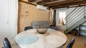 A dining area with a round table, chairs, a woven centerpiece, and a stone wall.