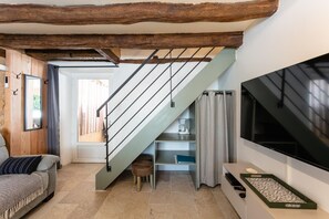 A modern living room with a staircase, a sofa, a coffee table, and a flat-screen TV.