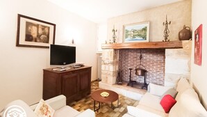 Una sala de estar con chimenea, televisor y sofá.