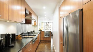 A modern kitchen with wooden cabinets, stainless steel appliances, and a black countertop. - The Diplomat #3 - Boutique Designer Home (New York)